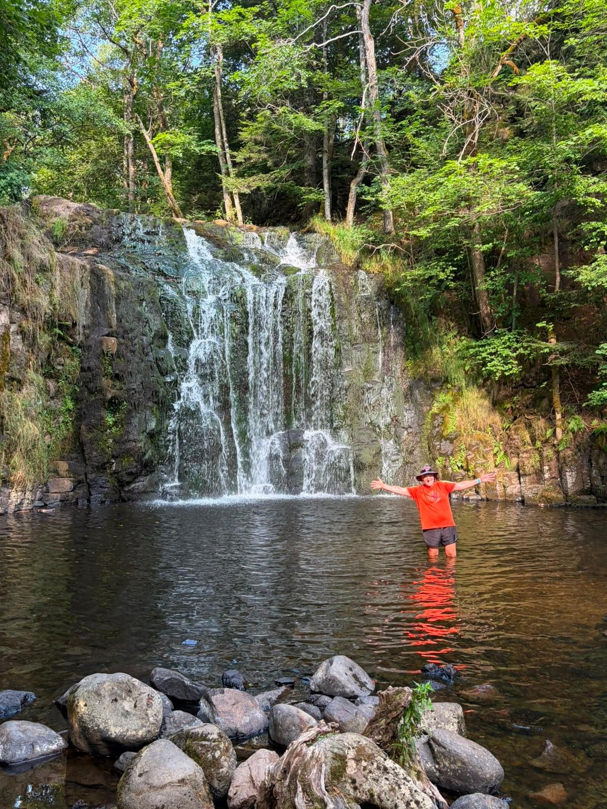 Cyrille dans l'eau devant une cascade du parcours